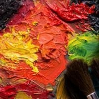 Nahaufnahme von dicker, strukturierter &Ouml;lfarbe in Gelb, Orange, Rot und Gr&uuml;n mit zwei Pinseln