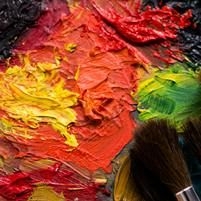 Nahaufnahme von dicker, strukturierter &Ouml;lfarbe in Gelb, Orange, Rot und Gr&uuml;n mit zwei Pinseln